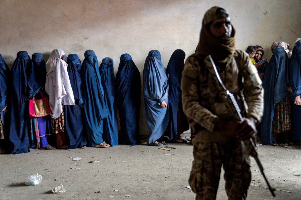 塔利班嚴格限制阿富汗女性的工作、教育與行動自由。圖為女性身穿罩袍排隊等候人道組織...