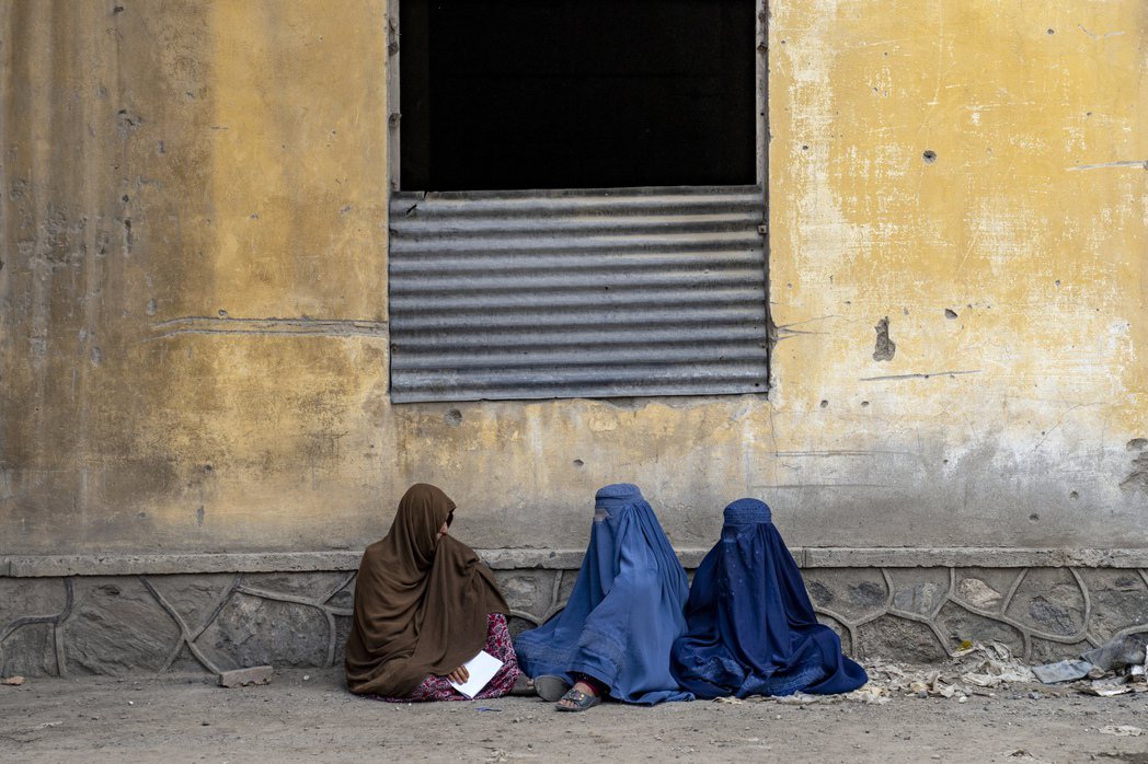 阿富汗女性身穿罩袍，等候人道組織發放糧食。 圖／美聯社