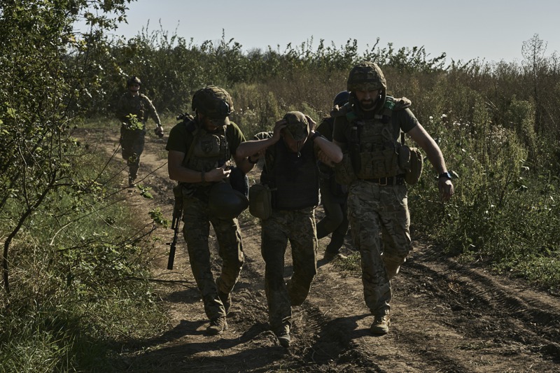 烏克蘭軍人8月30日在烏東頓內次克州巴赫姆特前線協助撤離一名受傷同袍。美聯社
