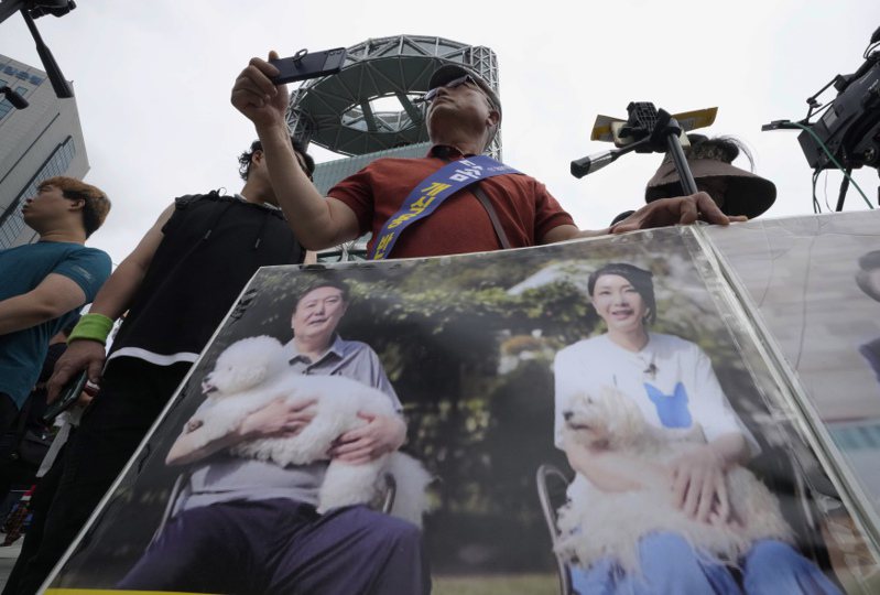 南韓動物權益維護者今年7月在抗議南韓吃狗肉的活動中，舉著總統尹錫悅與夫人抱著狗的照片。  美聯社