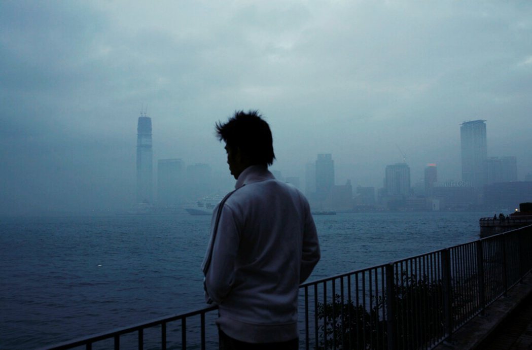 2009 年 2 月，一名男子在大霧裡眺望香港維多利亞港。 圖／美聯社