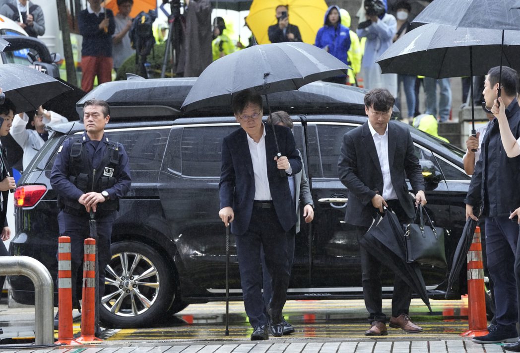 南韓最大在野黨、共同民主黨黨魁李在明（中）今天上午柱著拐杖，進入首爾中央地方法院...