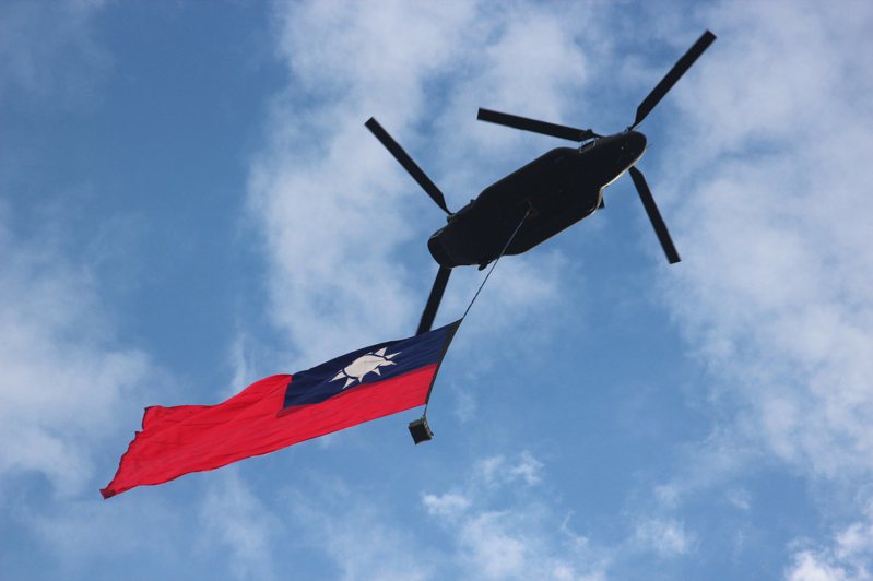 國軍28日展開國慶日前的空中全兵力預演，懸掛巨幅國旗的CH-47SD運輸直升機飛越總統府前上空，場面壯觀。 中央社
