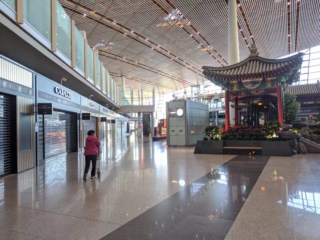 北京首都機場30日進入長假第二天，出境航廈的免稅店幾乎仍大門深鎖。（記者廖士鋒／...