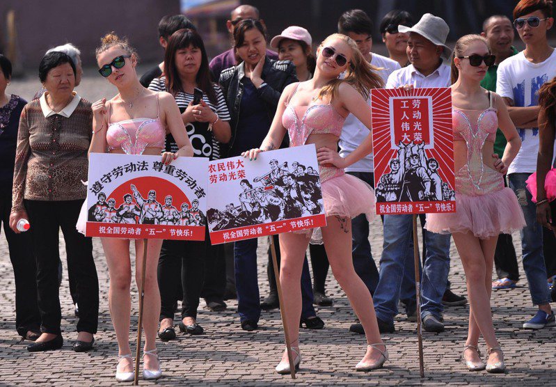 重慶洋人街上，幾名外國美女手舉「中國夢，勞動美」、「工人偉大，勞動光榮」、「遵守勞動法，尊重勞動者」等宣傳牌，吸引路人駐足。中新社資料照片