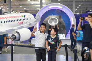 C919成功起飛，一圓了中國人的航空夢。圖為9月在北京舉行的全國科普日活動上，兩名孩童正在觀看C919的模型。新華社