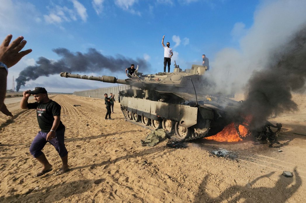 巴勒斯坦人在加薩圍欄旁站上一輛被摧毀的以色列坦克慶祝。 圖／美聯社  