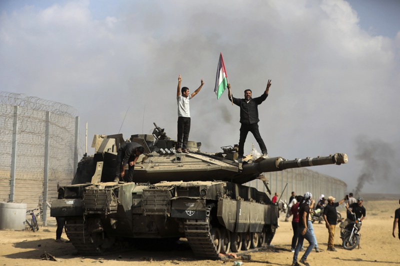 加薩地區激進組織哈瑪斯的武裝分子7日攻進以色列邊界，在一輛被摧毀的以色列戰車上慶祝勝利。專家指這次攻擊對以色列的心理衝擊堪比美國911恐怖攻擊。美聯社