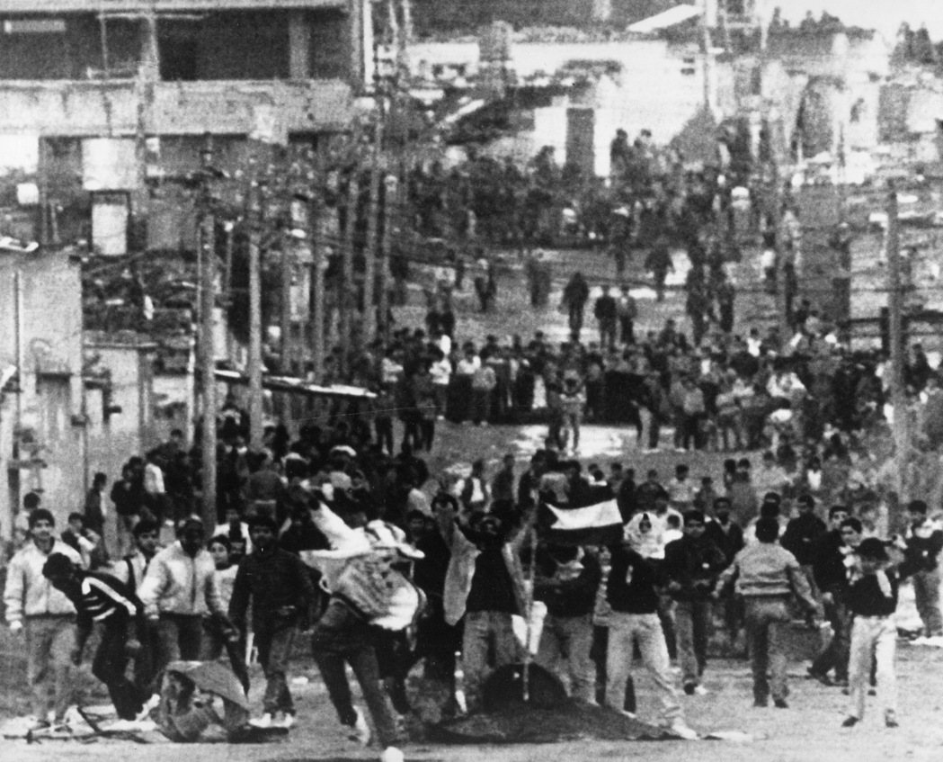 1987年「大起義」的巴勒斯坦街頭，民眾揮舞國旗。 圖／美聯社