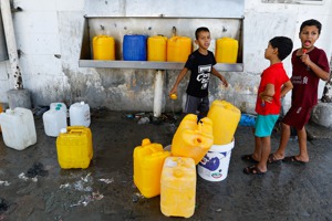 在加薩走廊南部城市汗尤尼斯，巴勒斯坦孩童帶著塑膠桶到公共水龍頭裝水，儲備用水。照片攝於11日。路透