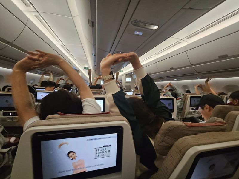 布萊N拍下飛機上乘客一起做伸展操的畫面。圖／擷自「布萊N 機票達人」