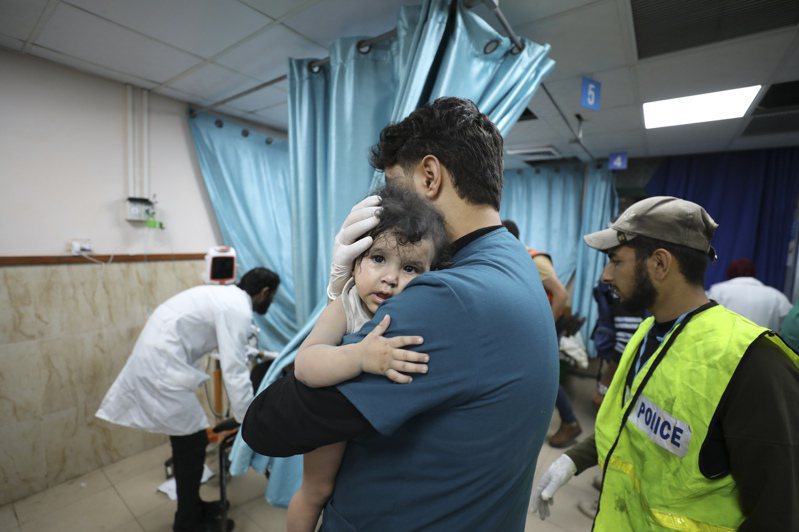 美国CNN报导，一些加萨家长会将子女的名字写在其腿上，以便在自己或者子女被杀时便于辨识遗体身分。图为10月22日，巴勒斯坦医务人员在戴尔艾拜莱抱着一名在空袭中受伤的儿童。美联社(photo:UDN)