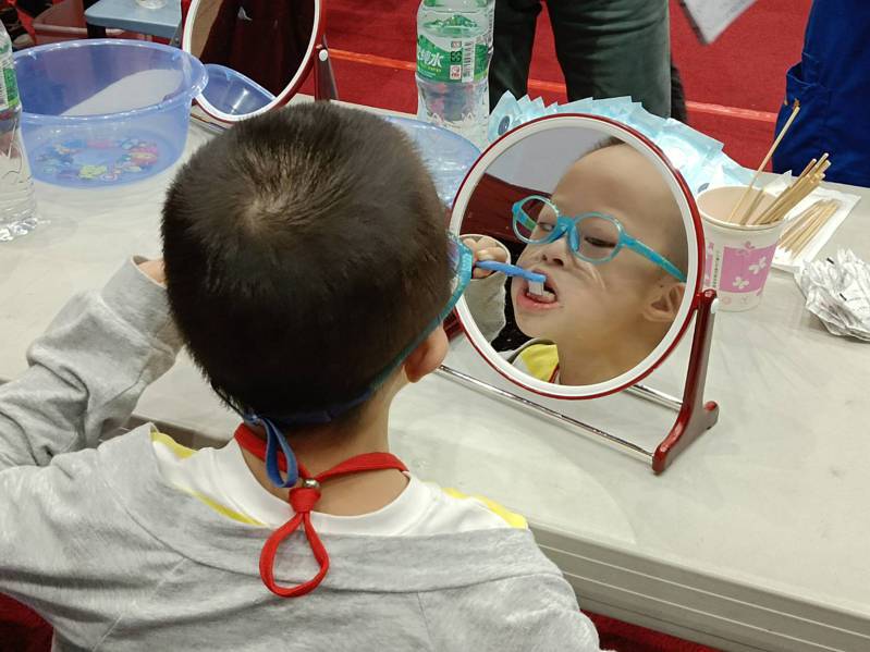 參賽的孩子一邊刷牙、一邊照鏡子，了解自己刷牙是否正確及刷乾淨。記者戴永華／攝影