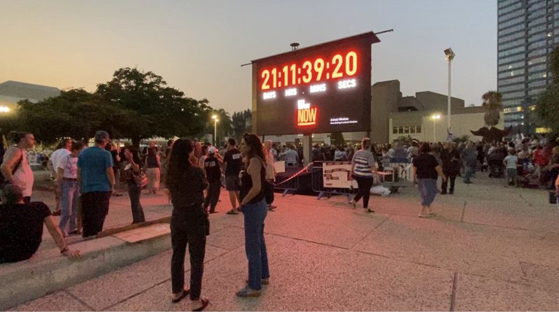 位處特拉維夫市中心、緊鄰以色列國防部的特拉維夫藝術博物館前廣場10天前就透過不同創意擺飾，聲援人質家屬。廣場上引人注目的大型LED紅色數字看板，提醒民眾人質危機已近22天。中央社