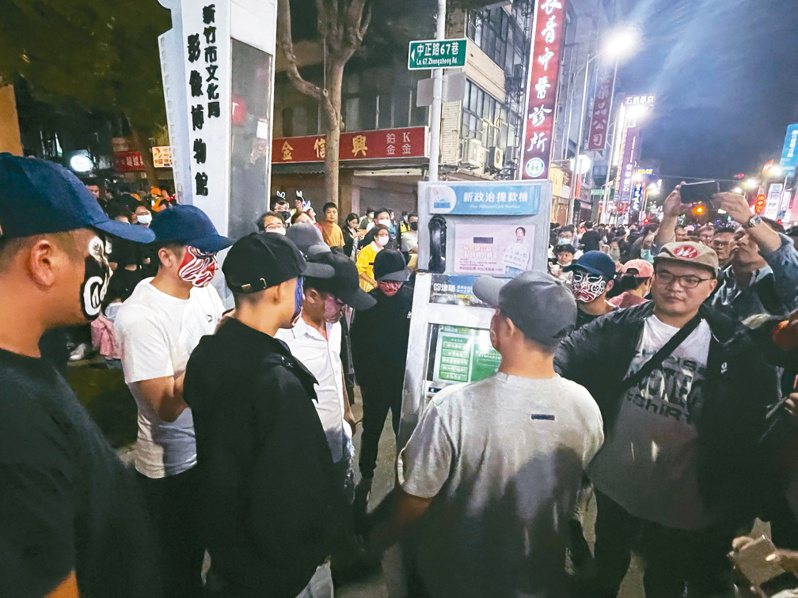 黑衣、畫臉譜男子出現在「新政治提款機」旁不停抽菸，被警方帶離。記者張裕珍／攝影
