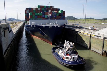 一艘拖船拖著貨櫃輪通行巴拿馬運河。路透
