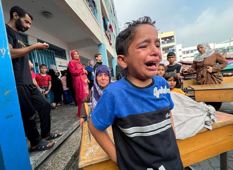 巴勒斯坦加薩走廊賈巴利亞難民營一所聯合國管理的學校正充當避難所，2日據報受到以色列襲擊的波及，一名男孩哭著稱「他們沒有做錯事」。路透