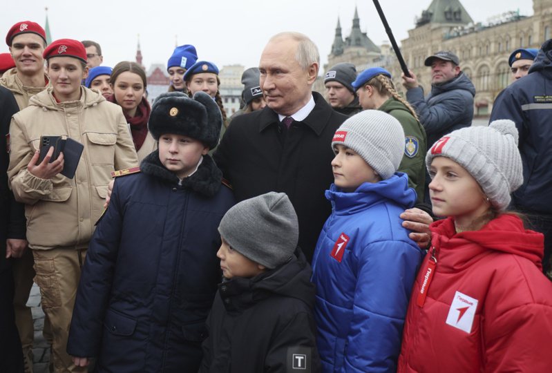 俄国总统普亭（中）四日在莫斯科红场，与俄国青年组织「青年军学员国民运动」成员及俄乌战争阵亡官兵家属合照。有外交官指出，普亭在俄国国内支持度高达百分之八十。（美联社）(photo:UDN)
