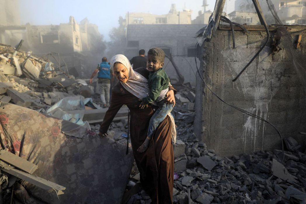 以色列空襲加薩中部難民營社區後，居民攜帶孩子們逃離。 圖／法新社