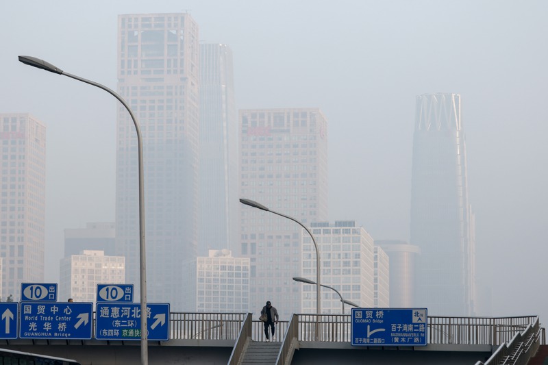 科學家指出，中國清除空氣汙染反而失去能抵擋陽光的二氧化硫防護，從而使氣溫升高。圖為北京一名男子今年10月在霧霾經過天橋。歐新社
