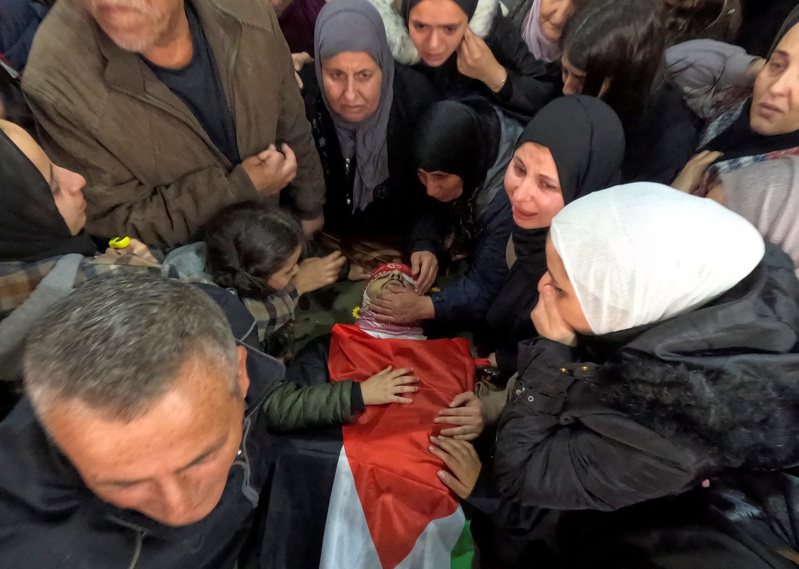 以色列與哈瑪斯組織於加薩走廊交戰之際，約旦河西岸暴力衝突隨之激增。巴勒斯坦紅新月會表示，以軍今天突襲約旦河西岸，至少殺害兩名巴勒斯坦人。圖為約旦河西岸的伯利恆，在以色列襲擊中被殺的巴勒斯坦人的葬禮上，親屬們在他的屍體旁哀悼。路透