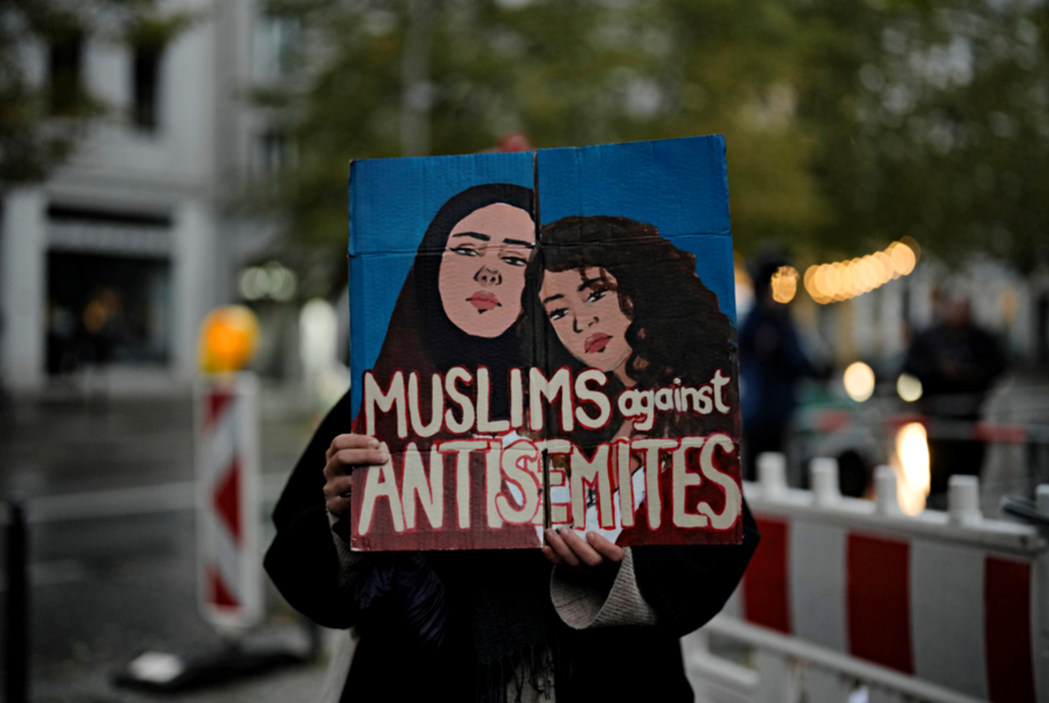 一名柏林穆斯林女姓在守夜活動中展示反對反猶太主義的海報。 圖／美聯社