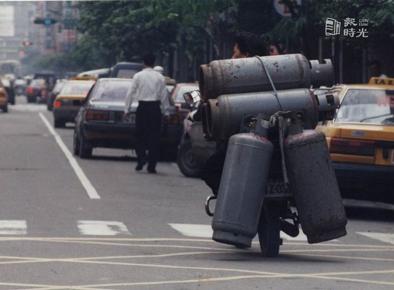 這輛機車一口氣載了五個瓦斯桶後掛的兩桶幾乎已貼地而行，送瓦斯的先生本領高強，行經台北街頭有如特技表演。圖／聯合報系資料照(1994/12/20  杜建重攝影)