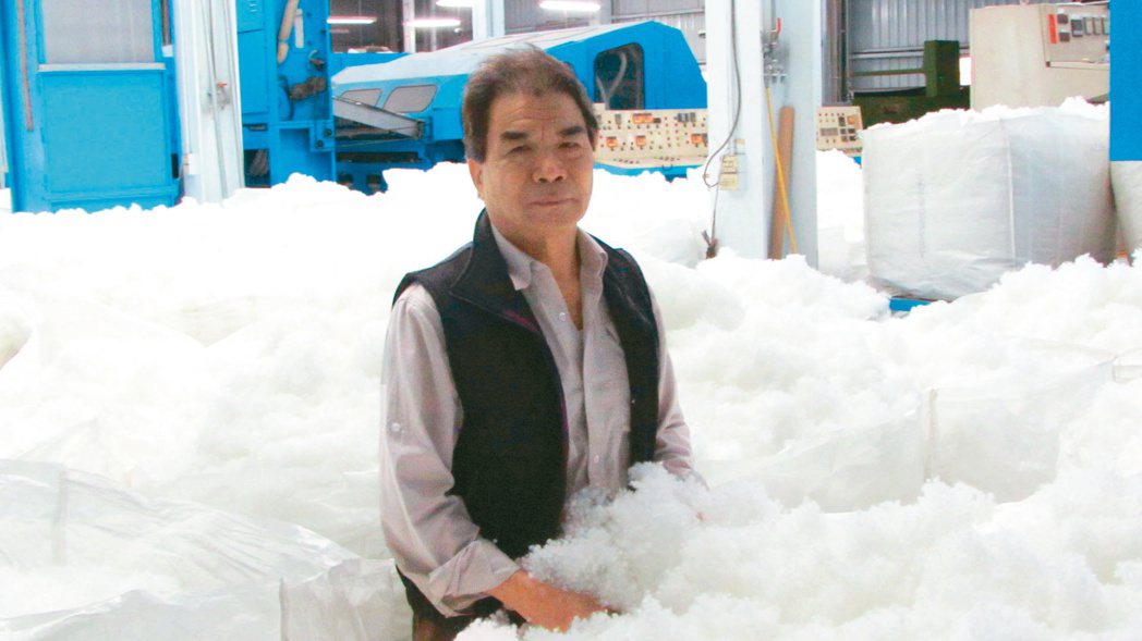 國統毯業董事長葉聰明置身於有如白色泡沬的科技絨球原料堆。翁永全／攝影