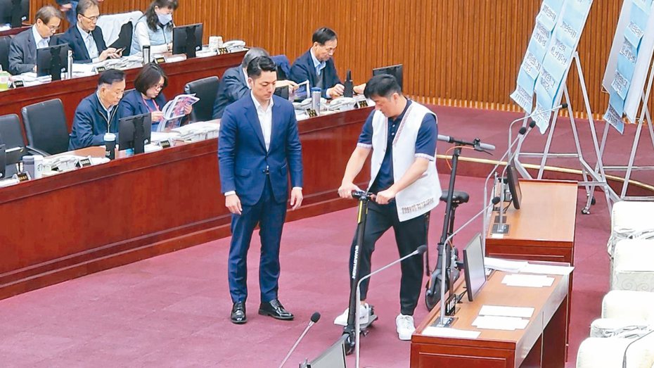 市長蔣萬安昨天赴議會總質詢，議員李傅中武在議場秀出兩輛電動滑板車，要蔣萬安試騎看看。記者楊正海／攝影