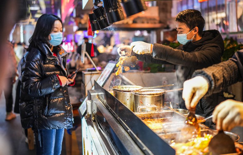 11月財新中國通用服務業採購經理人指數（服務業PMI）為51.5，較10月回升1.1個百分點，為近三個月來最高。圖為中國民眾在貴州省貴陽市南明區「青雲市集」購買特色小吃「烤米皮」。（新華社）