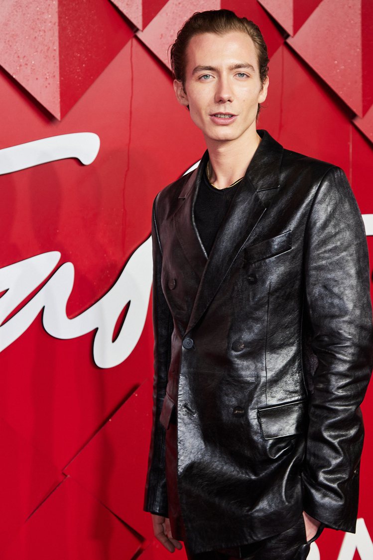英國模特兒Paul Hameline穿著以皮革效果處理的亞麻黑色雙排扣西裝外套與...