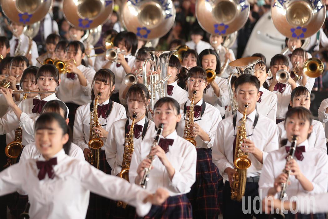 日本京都橘高校吹奏樂部今天早上在高雄承億酒店1樓戶外廣場加碼快閃演出，整齊劃一的...