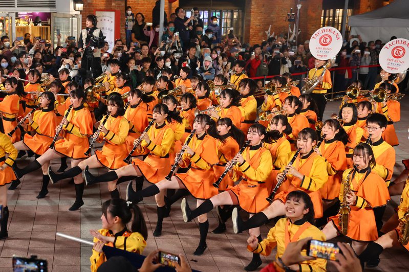在台灣掀起「橘色旋風」的日本京都橘高校吹奏樂部12日現身台北紅樓廣場，「橘色惡魔」演奏動感曲目搭配活潑肢體動作，炒熱現場氣氛。圖／中央社