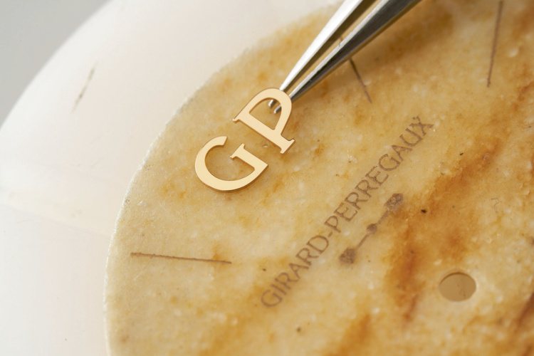 在鵝卵石的面盤上，表匠並將代表品牌的GP字樣細心鑲嵌。圖／Girard Perregaux提供