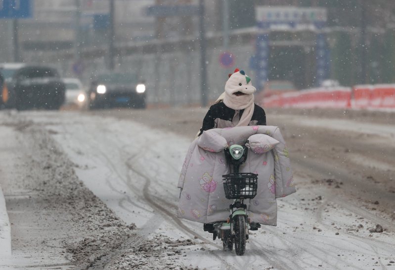 北京降雪天氣持續，市民冒雪騎車出行。圖／中新社