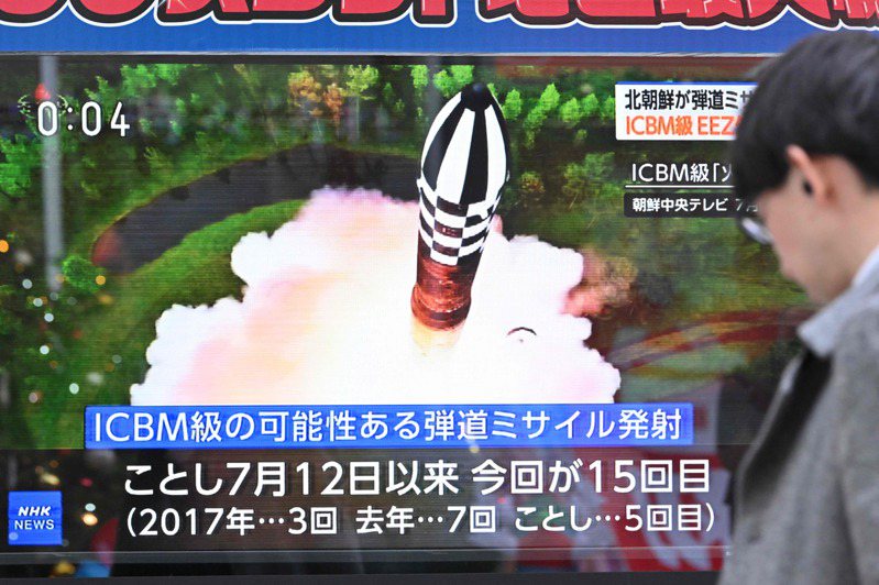 一名男子十八日走過東京街頭的電視螢幕，畫面正播報北韓試射洲際彈道飛彈新聞。（法新社）