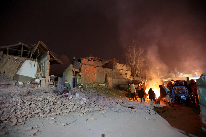 低溫恐將導致這次甘肅地震的黃金救援時間縮短。圖為地震後，當地民眾在戶外生火取並躲避餘震。（美聯社）