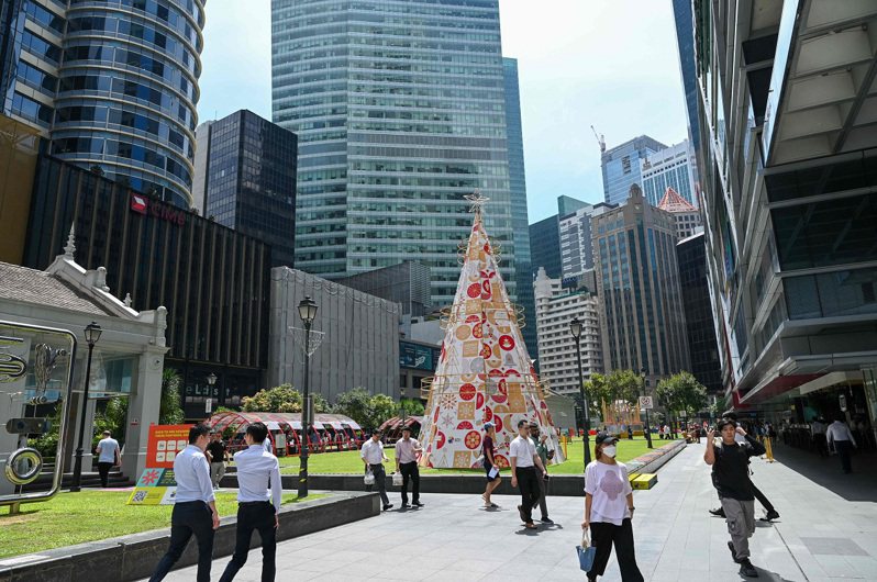 新加坡民眾5日走過萊佛士坊金融區的耶誕裝飾。法新社