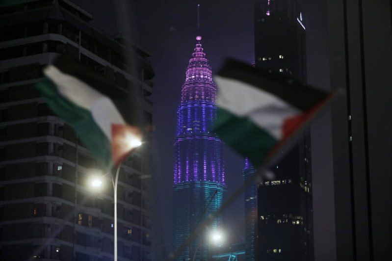 大馬吉隆坡地標國油雙峰塔跨年夜以變色燈光秀取代煙火秀，圖為社運人士凌晨在變色燈光秀展開之際在美國使館前揮舞旗幟，表達聲援巴勒斯坦訴求。中央社 中央通訊社