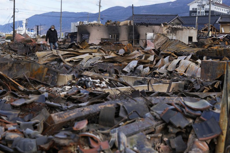日本石川縣輪島發生地震後，一名男子4日在走在毀壞的建築殘骸上。歐新社