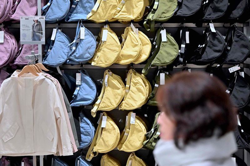 日本平價服飾品牌Uniqlo今天正控告中國競爭對手、快時尚線上零售商Shein，指控對方仿冒該品牌一款大受歡迎的肩背包。圖為一名女子走過東京一家Uniqlo零售店的包款展示架。法新社