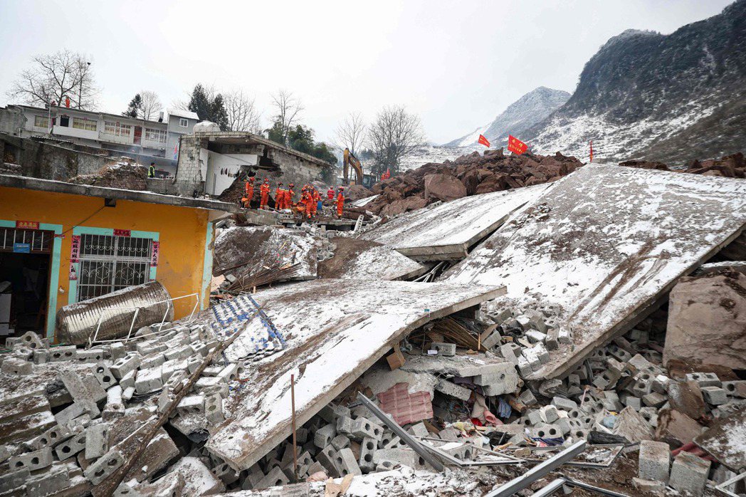 雲南省22日山體滑坡意外，可以看到房屋建材與磚瓦被沖刷倒塌。身穿橘色制服的救難隊...