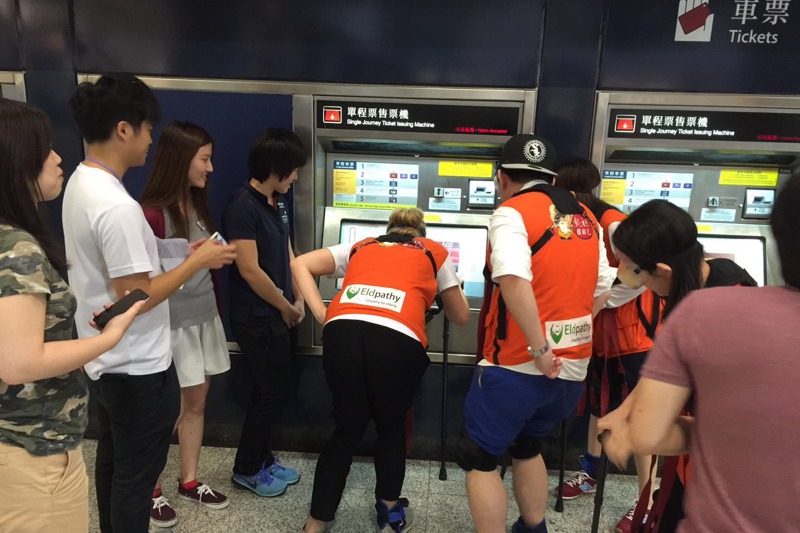 在社會企業歷耆者的協助下， 一群年輕人穿戴裝置，體驗八旬長者買票搭地鐵。圖／歷耆者提供