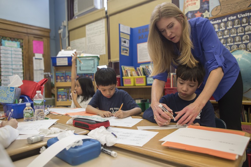 美國紐約皇后區1名教師（右）2017年3月在課堂協助3年級學生練習草書。美聯社