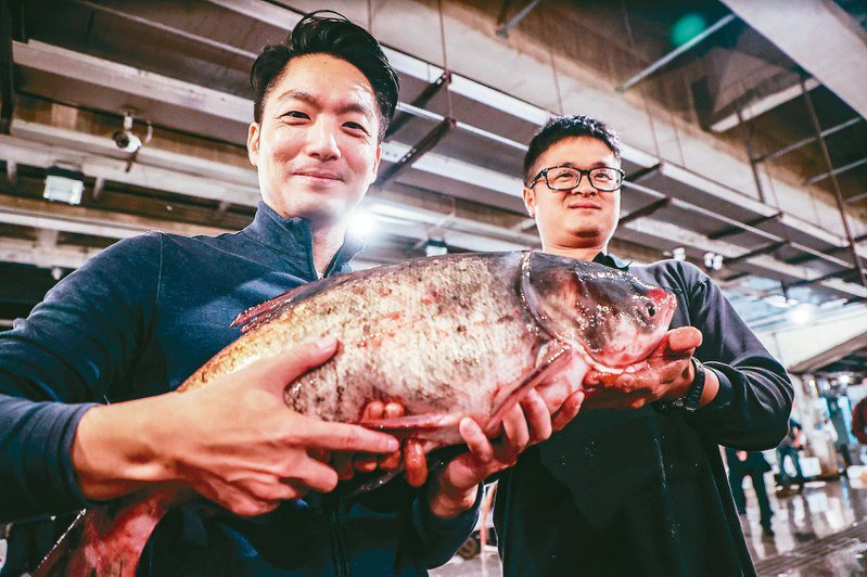 台北市長蔣萬安（左）昨天清晨前往萬大魚類批發市場視察。蔣萬安抱起一尾大頭鰱，關心業者銷售狀況。記者曾原信／攝影