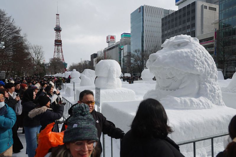 日本北海道冬季特色活動之一的「札幌雪祭」今天在札幌市開幕，這是受COVID-19疫情影響睽違4年再度在3個會場大規模舉辦，總計展出196座雪雕及冰雕。圖為北海道札幌冰雪節期間，人們與雪雕合影。法新社