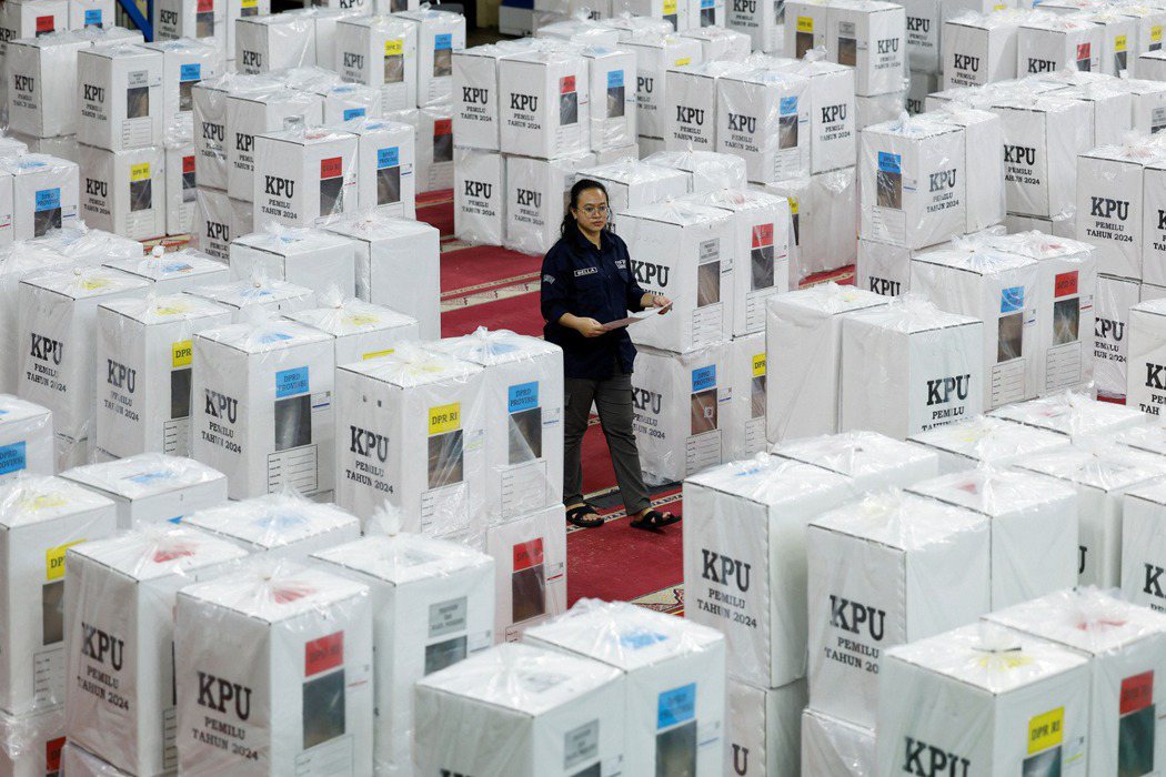2024 年 2 月 6 日，印尼雅加達，一名選舉委員會官員經過擺滿投票箱的走道...