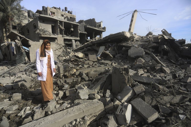 一名巴勒斯坦婦女走過以色列轟炸加薩地帶的廢墟。(美聯社)