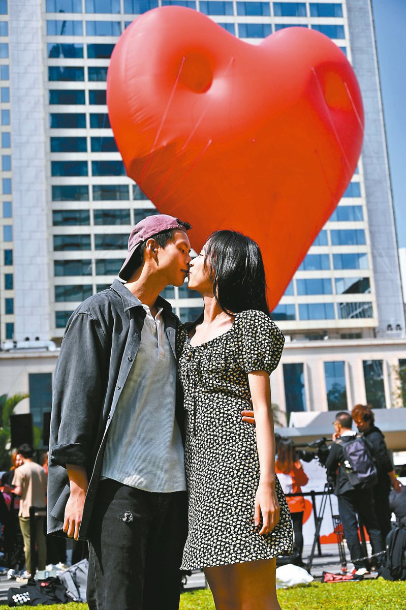 昨天是西洋情人節，香港特區政府特別在中環皇后像廣場裝置巨型紅心氣球，吸引許多情侶前來拍照打卡。（中新社）