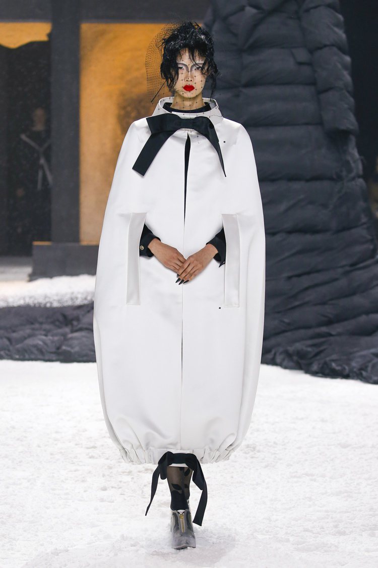 THOM BROWNE 2024秋冬系列，模特兒穿著斗篷是以白色絲緞與黑色波紋絲綢製成，搭配蝴蝶結點綴。圖／THOM BROWNE提供